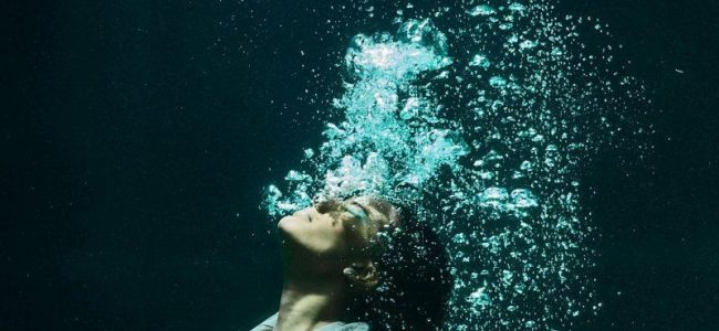 Woman underwater in suit with air bubbles