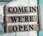 Shop's come in we're open sign on a blue door