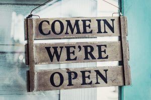 Shop's come in we're open sign on a blue door